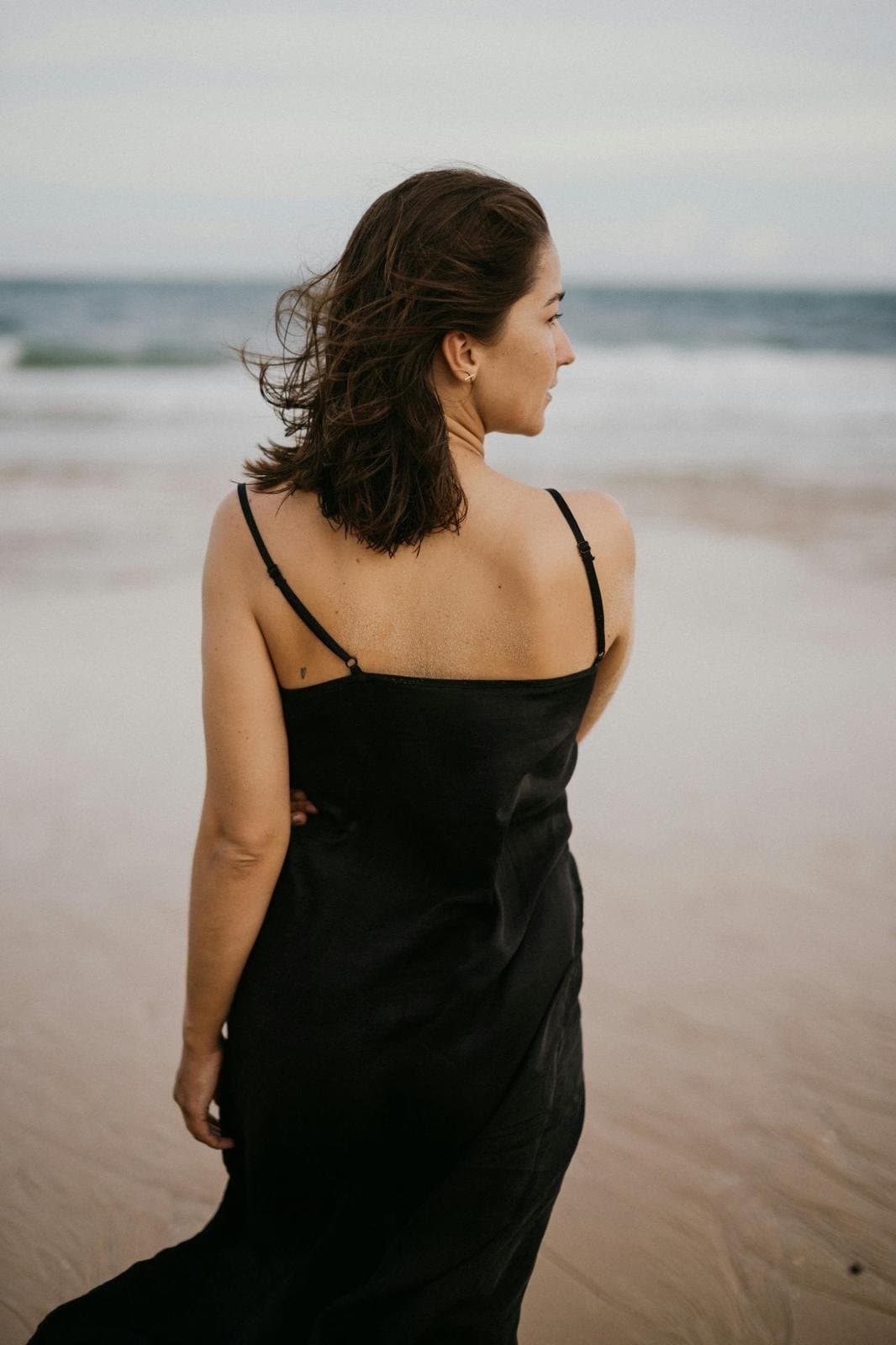 Beach editorial portrait in a black dress photographed with natural movement